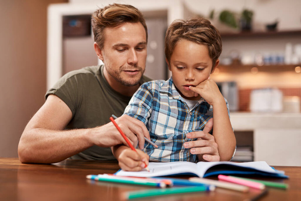 Ты молодец, приятель. мужчина, сидящий со своим сыном, пока он делает свою домашнюю работу - Фото, изображение
