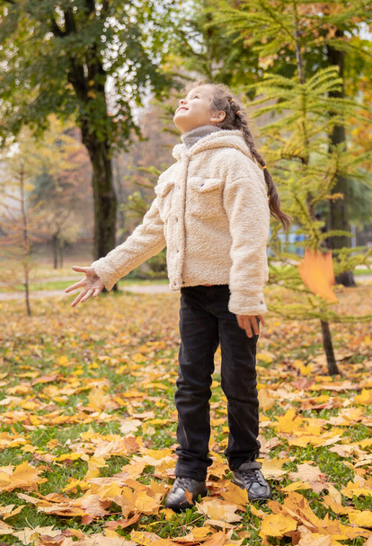 Portret pięknej dziewczyny jesienią. Pomarańczowe i żółte liście na drzewach. Październik. Spacer po parku z dziećmi. - Zdjęcie, obraz