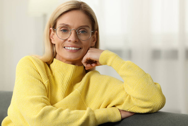 Happy woman in stylish glasses on sofa indoors - Foto, afbeelding
