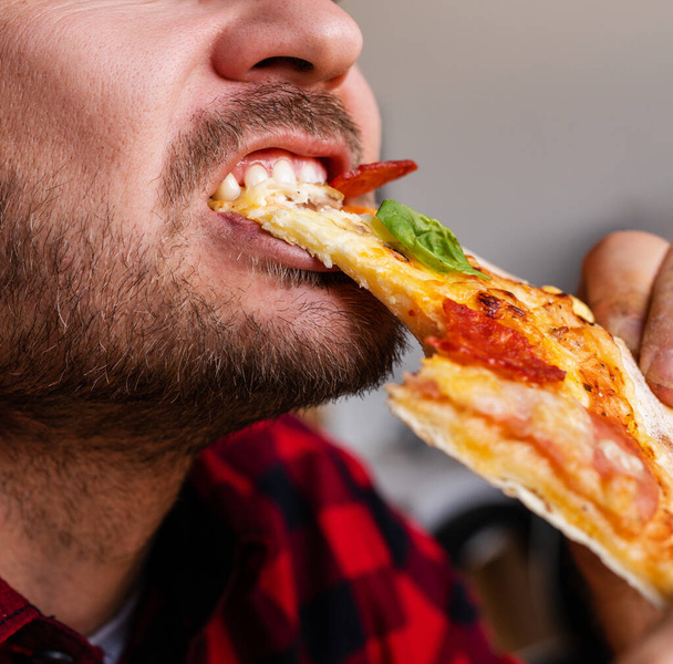 Männliche bärtige Person isst Pizza Nahaufnahme Fotografie. - Foto, Bild