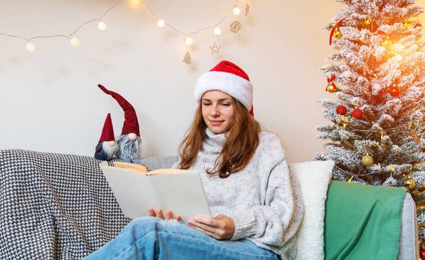 infantil, inmadurez. Mujer adulta joven lee un cuento de hadas mientras que la Navidad. - Foto, Imagen
