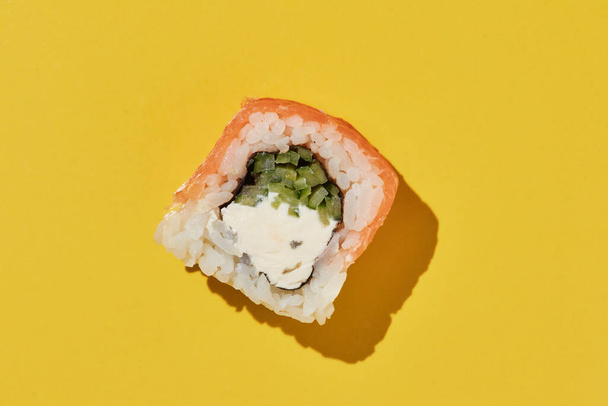 Filadélfia de rolo de sushi fresco com salmão, queijo e pepino em fundo amarelo, vista superior. - Foto, Imagem