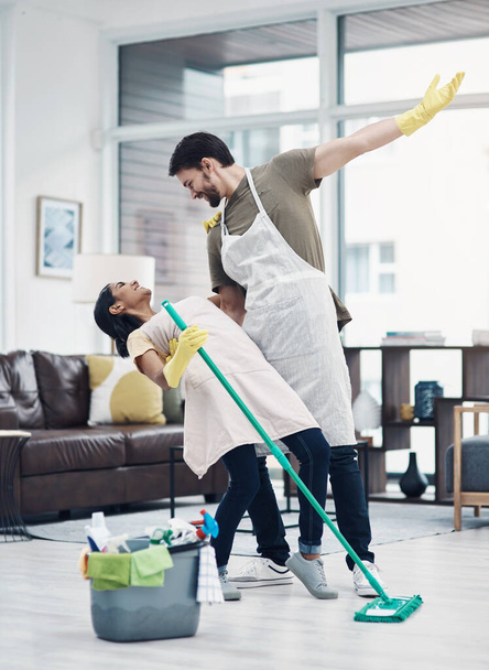 Niente ispira produttività come la passione. una giovane coppia felice che balla mentre pulisce il pavimento a casa - Foto, immagini