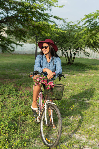 Latijnse vrouw draagt bloemen in de fietsmand - Foto, afbeelding