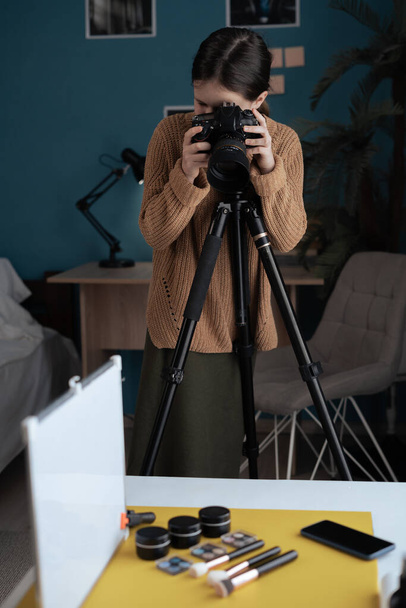 Γυναίκα φωτογράφος φωτογραφίζει ένα καλλυντικό προϊόν σε ένα στούντιο στο σπίτι. Παιδικά χόμπι και επαγγέλματα. Αντιγραφή χώρου - Φωτογραφία, εικόνα
