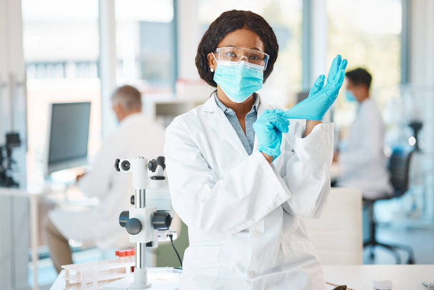 Готов к лабораторным работам. Портрет молодого учёного, надевающего перчатки во время работы в лаборатории - Фото, изображение