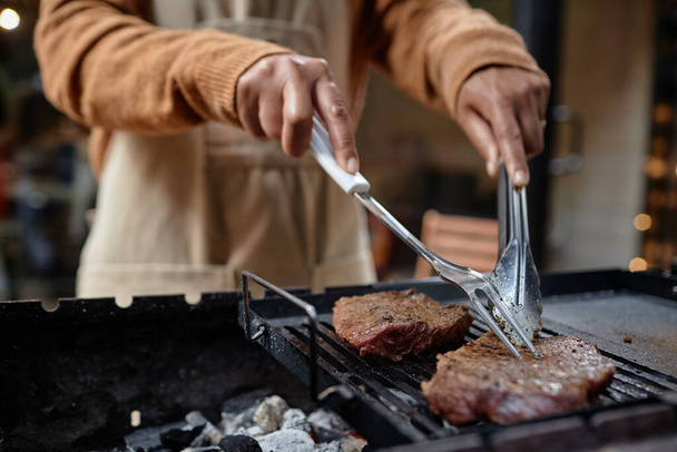 Primo piano della donna che prepara bistecca di carne alla griglia durante il picnic all'aperto - Foto, immagini