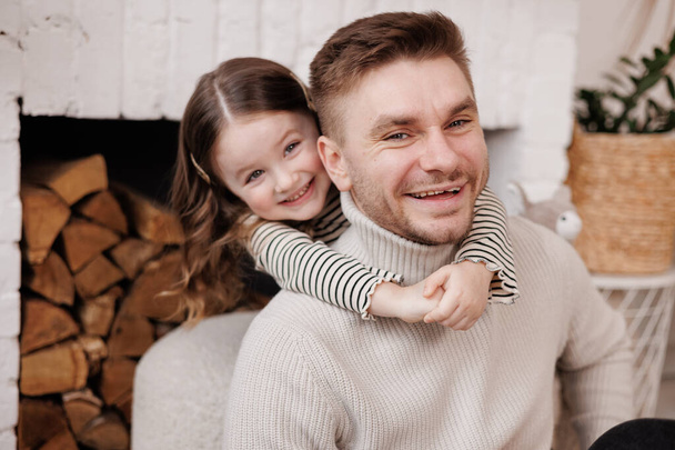 Happy father's day. Adorable child daughter and young single dad are embracing and kissing at home, feeling love and affection. Family of two is having fun and spending time together. - Photo, Image