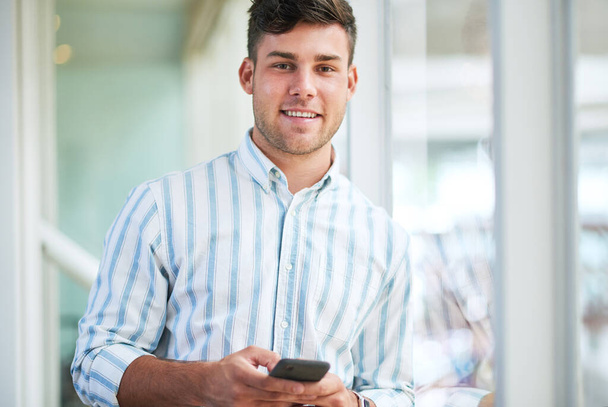 Удобно, как это удобно для пользователя. молодой бизнесмен, использующий смартфон в современном офисе - Фото, изображение