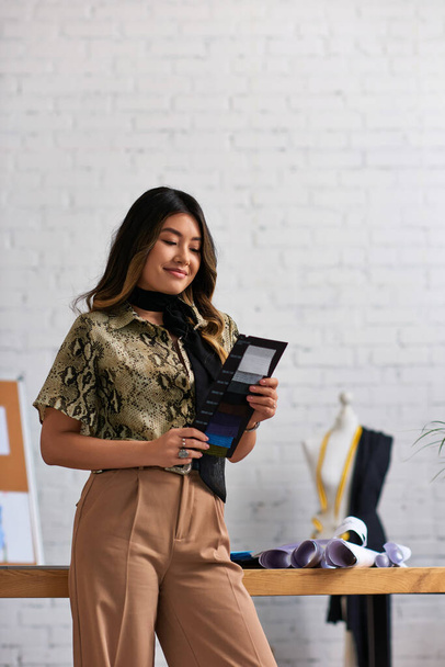 veselé asijské oblečení stylista drží barevné vzorníky v soukromé módní ateliér, inspirace - Fotografie, Obrázek