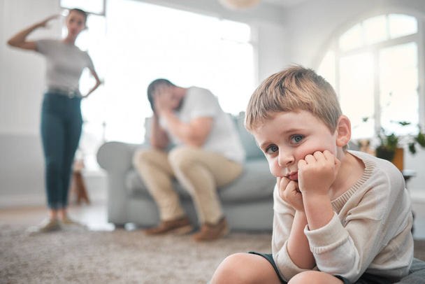 Ένας άνθρωπος, όσο μικρός κι αν είναι. ένα μικρό αγόρι που δείχνει λυπημένο ενώ οι γονείς του τσακώνονται στο σπίτι - Φωτογραφία, εικόνα
