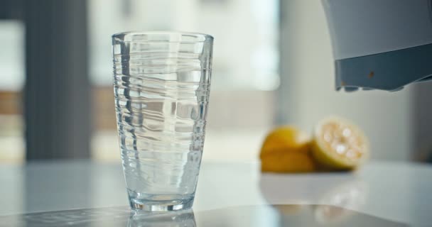 Κοντινό βίντεο αργής κίνησης με χυμό εσπεριδοειδών να χύνεται σε ένα ποτήρι στην κουζίνα. Ιστορικό βίντεο του βιολογικού φρέσκου χυμού πορτοκάλι ποτό στο εσωτερικό του σπιτιού. Υψηλής ποιότητας 4k πλάνα - Πλάνα, βίντεο