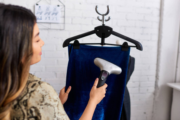 elmosódott ázsiai stylist gőzölgő minőségi velúr szövet a modern divat atelier, sikeres üzlet - Fotó, kép