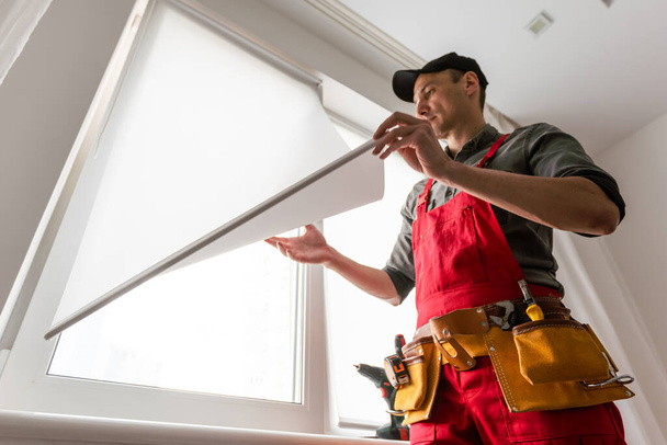 Pracovník instaluje rám okna master sverdit pro připojení k základní opravě ve výškových budovách. Kvalitní fotografie - Fotografie, Obrázek