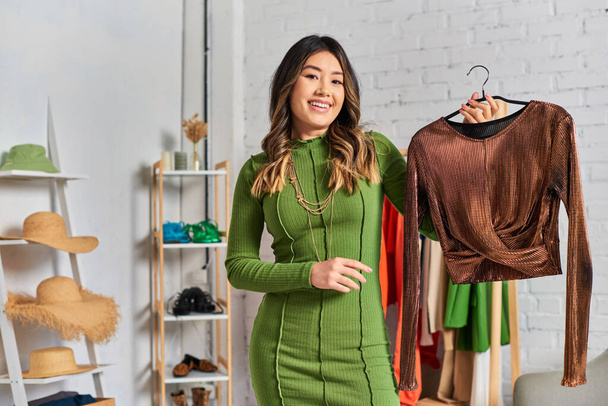 asiatische persönliche Stylistin mit eleganter maßgeschneiderter Bluse vor der Kamera im eigenen Atelier, Kleinunternehmen - Foto, Bild