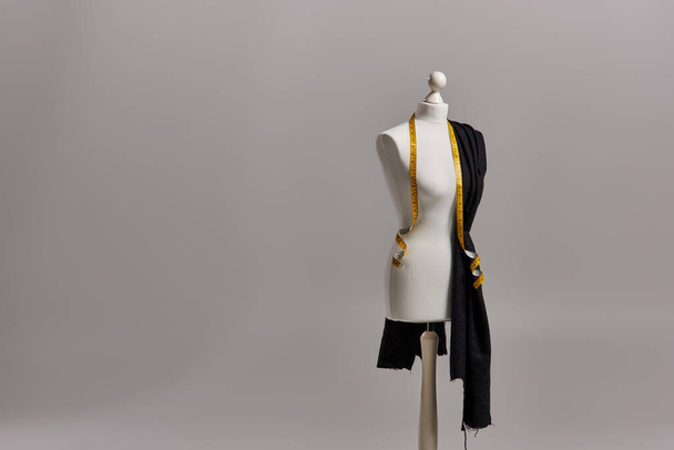 манекен на тринозі з якісною тканиною та вимірювальною стрічкою на сірому фоні, одягу - Фото, зображення