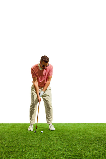 Junger Mann im roten T-Shirt beim Schwingen auf dem Golfplatz auf grünem Gras im Golfclub. Konzept von Spiel, Sport, Erholung, gesunder und aktiver Lebensweise. Kopierraum für Werbung - Foto, Bild