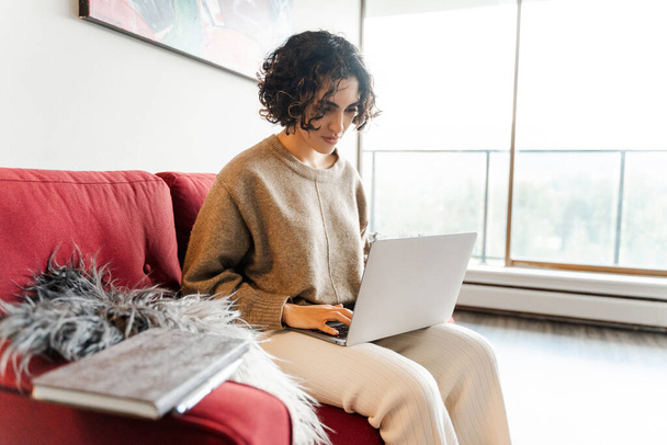 Portret uśmiechniętej pozytywnej kobiety przygotowującej się do wideokonferencji, korzystającej z laptopa pracującego online z domu, zdalnej pracy. Atrakcyjna studentka, przygotowująca się do egzaminu. Koncepcja edukacji internetowej  - Zdjęcie, obraz