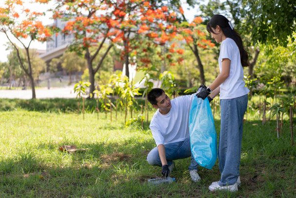 Gelukkige jonge Aziatische studenten diverse vrijwilligers met vuilniszakken schoonmaak gebied in het park, Het concept van milieubehoud op de wereld dag van het milieu, recycling, liefdadigheid voor duurzaamheid. - Foto, afbeelding
