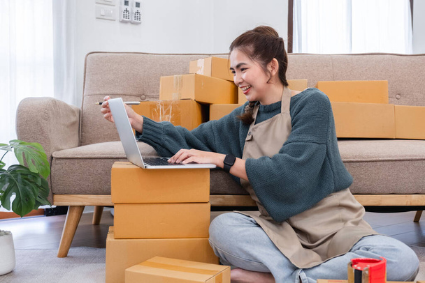 Startup small business entrepreneur SME, asian woman packing cloth in box. Portrait young Asian small business owner home office, online sell marketing delivery, SME e-commerce telemarketing concept. - Photo, Image