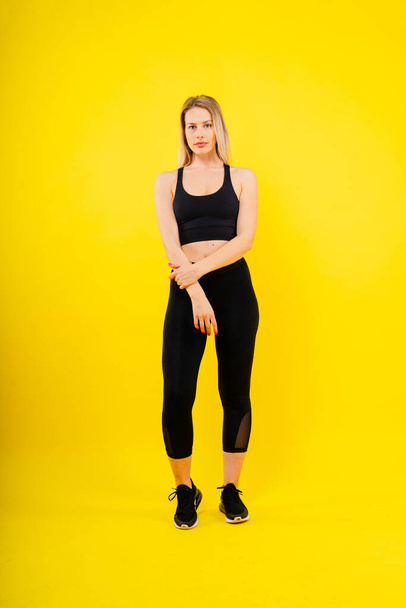 Jeune femme, posant en studio. Vêtements de sport publicitaires et vêtements de yoga. Mode de vie sain, sport - Photo, image