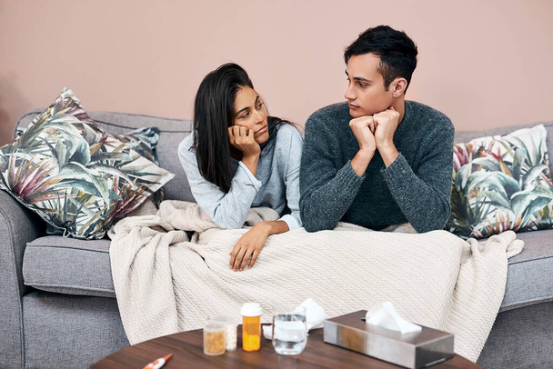 Self quarantine can lead to feelings of stagnation. a young couple sitting on the sofa while recovering from an illness at home - Photo, Image