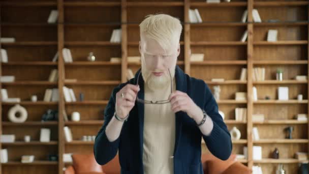 Homme d'affaires albinos portant des lunettes élégantes au bureau. Un homme confiant croisant les bras à l'intérieur. Un cadre sérieux posant à la caméra de la bibliothèque. Portrait d'un gars fatigué se sentant surmené  - Séquence, vidéo