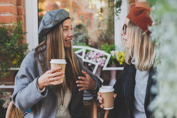 Mladá žena nejlepší přátelé mluvit spolu diskutovat zajímavá témata během volného času hipster dívky, vtipkování a baví společně těší rekreaci s kávou jít na městské - Fotografie, Obrázek