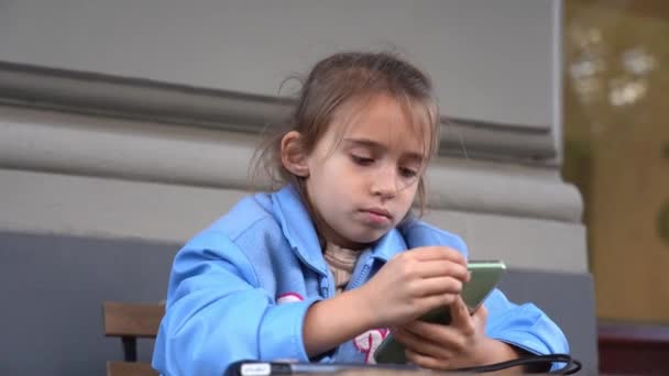 La fille utilisant un smartphone. jouer à des jeux ou regarder des informations. Enfant et gadget. - Séquence, vidéo