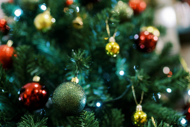 Bolas coloridas y guirnaldas luminosas cuelgan de un árbol de Navidad verde. Foto de alta calidad - Foto, imagen