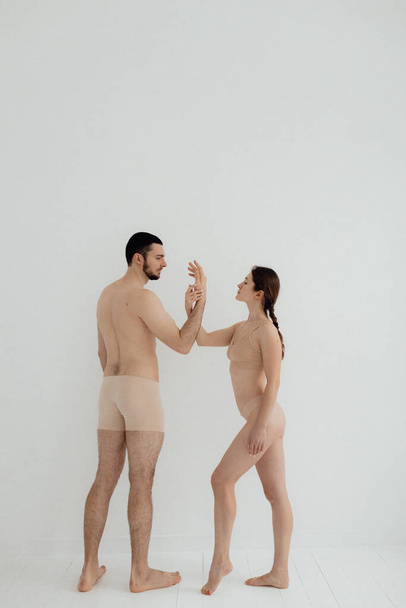 Cheerful woman and man standing on white background. Body positive young couple of lovers. No focus blurred and noise effect. - Фото, изображение