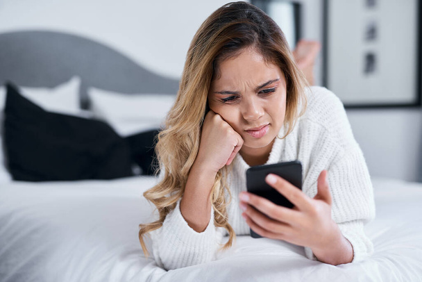 Az emberek a legfurcsább dolgokat posztolják. Egy fiatal nő használja a mobilját, miközben az ágyán fekszik. - Fotó, kép