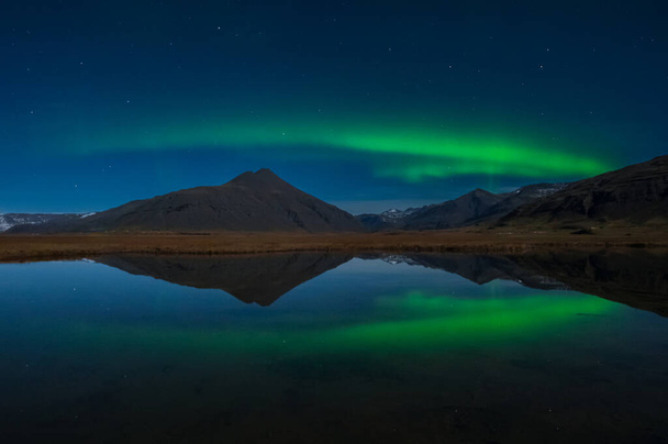 Aurora Borealis or Northern lights the amazing wonder of nature in the dramatic skies of Iceland. Night landscape with the green light in a beautiful dance reflected like a mirror - Fotografie, Obrázek