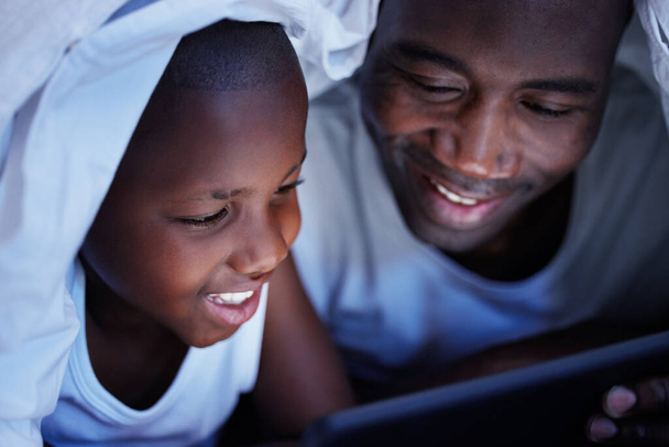 La familia es lo más importante del mundo. un padre y un hijo usando una tableta en la cama por la noche - Foto, imagen