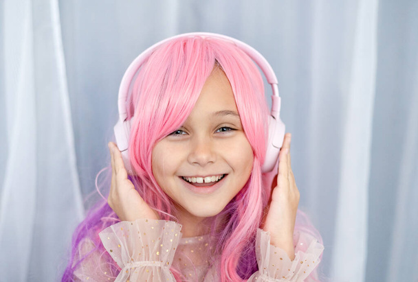 Βανίλια. Kawaii δονήσεις. Το κοριτσάκι με τα ροζ μαλλιά κάνει πάρτι σε στυλ Μπάρμπι. Ακούγοντας μουσική με ακουστικά - Φωτογραφία, εικόνα