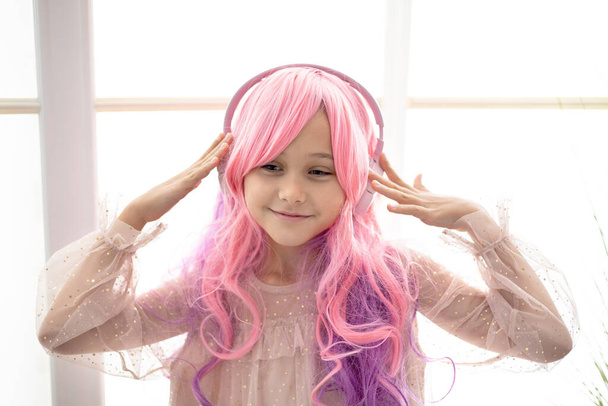 Vanilla Girl. Des vibrations kawaii. Petite fille aux cheveux roses faire la fête dans le style barbie. Écouter de la musique avec casque, téléphone portable. - Photo, image