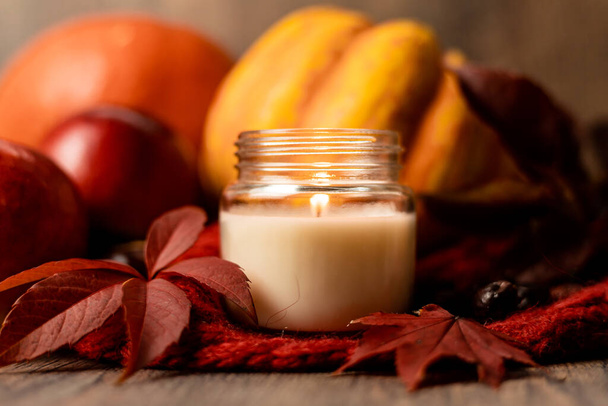 Burning candle on the table next to apples and grape leaves. Autumn Composition. High quality photo - Photo, Image