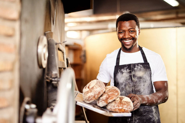 Теперь все, что тебе нужно немного масла. мужчина-пекарь держит свежеиспеченный хлеб в своей пекарне - Фото, изображение