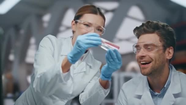 Successful doctors rejoicing research result discovering disease cure in laboratory close up. Smiling two scientists exploring new vaccine. Happy woman man researchers holding test tubes with drugs. - Footage, Video
