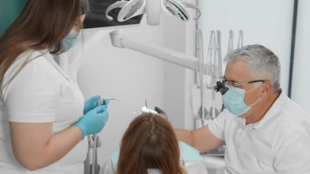 Diş hekimi ve asistanının ortak çabaları hastaların sağlıklarına kavuşmalarına ve gülümsemelerine yardımcı olur. Diş prosedürü hasta için maksimum rahatlıkla gerçekleştirilir. Yüksek kalite 4k görüntü - Video, Çekim