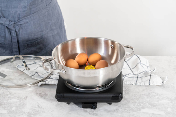 Bollire le uova biologiche marroni in una pentola per preparare le uova sode. - Foto, immagini