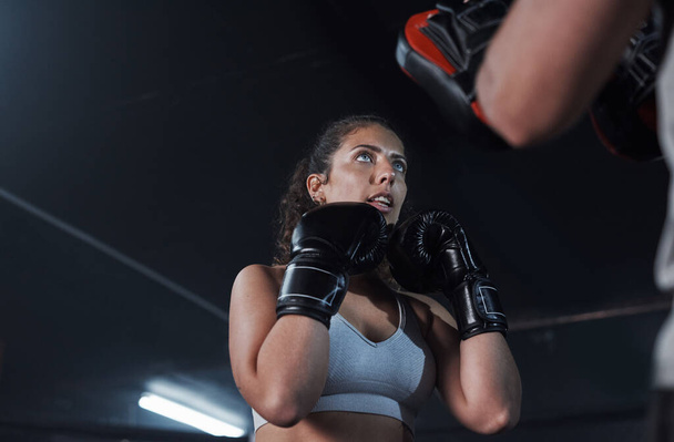 Чудовий спосіб підготуватися і захистити себе. молода жінка практикує зі своїм тренером у боксерському тренажерному залі - Фото, зображення