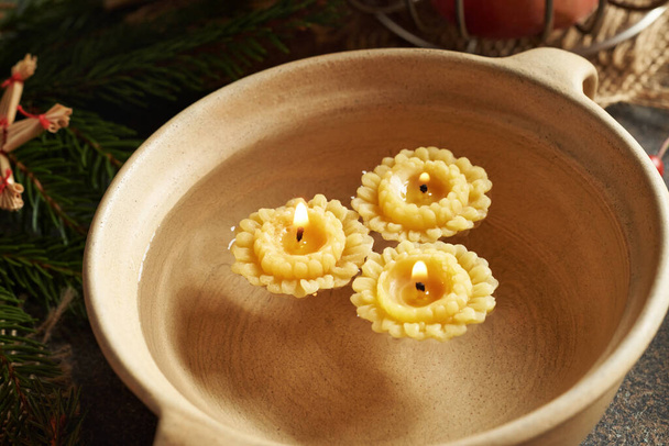 Velas de Navidad hechas de cera de abejas flotando en un tazón de agua - Foto, Imagen