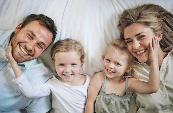 Een gezin dat samen ligt, blijft bij elkaar. Portret van een mooie jonge familie die met elkaar in bed praat en hecht - Foto, afbeelding