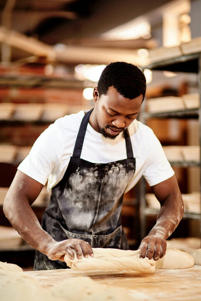 Everything is made with love and care. a male baker busy shaping dough at work - Photo, Image