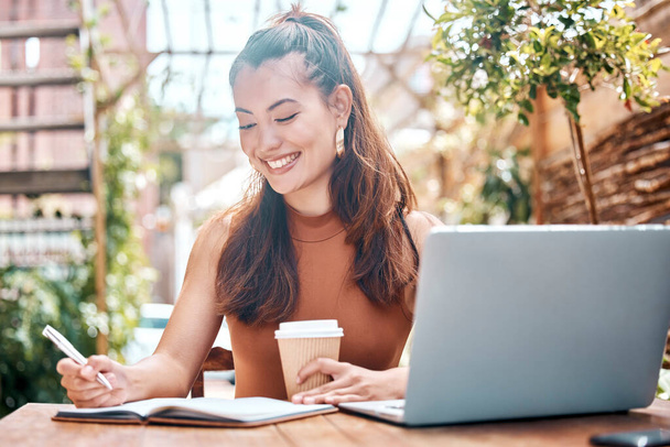 Gülümseyen genç iş kadını plan yapıyor, günlüğünü yazıyor ve kafede çalışırken kahve içiyor. İspanyol asıllı küçük işletme sahibi bilgisayarında çalışıyor, notlar alıyor. - Fotoğraf, Görsel