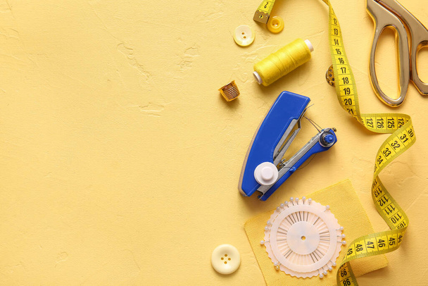 Máquina de costura manual com diferentes suprimentos no fundo amarelo - Foto, Imagem