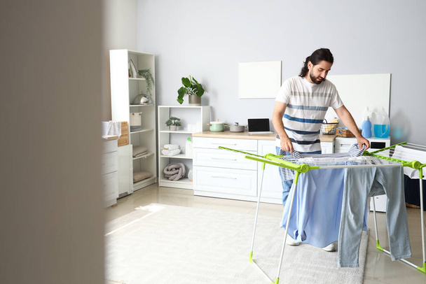 Giovane uomo appeso lavanderia su asciugatrice a casa - Foto, immagini