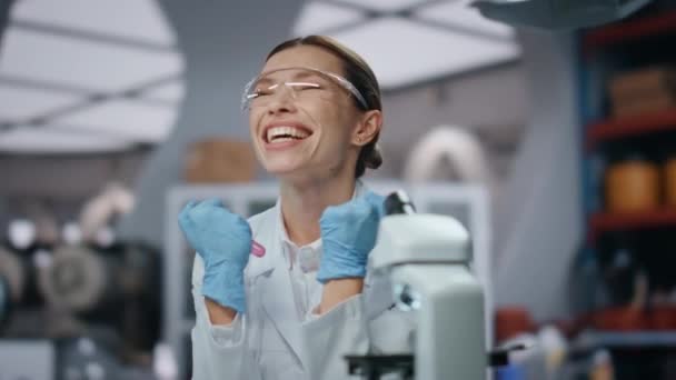 Elégedett laboratóriumi szakember mosolyog örül sikeres kutatás közeli. Izgalmas tudós kesztyűs szemüvegben, boldog a biokémiai laborban. Érzelmi női kutató gazdaság kémcső. - Felvétel, videó