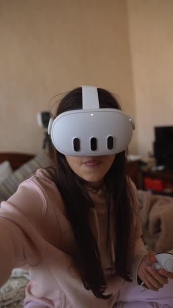 Ve svém růžovém pyžamu používá hezká dáma k hraní videoher soupravu VR. Vysoce kvalitní 4K záběry - Záběry, video
